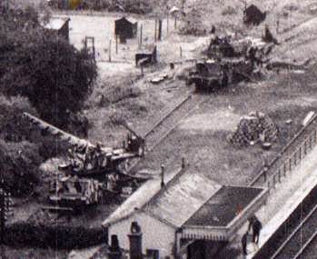 Detail from Aerial photograph of two rail-mounted howitzers.  The conventionally camouflaged gun is in the bottom left quadrant, the gun camouflaged by Cott is in the upper right quadrant.
